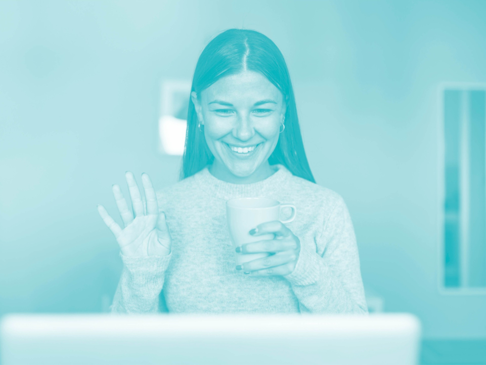 Eine Frau lächelt und winkt in den Laptop-Bildschirm während einer Videokonferenz.
